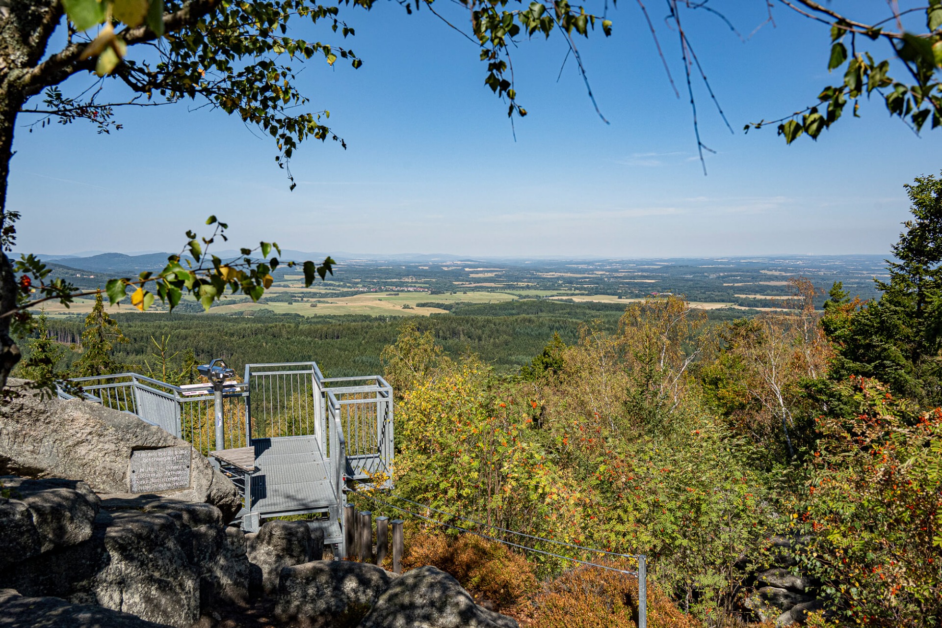 Aussichtspunkt mit Treppe und Geländer, Blick über bewaldete Täler und Felder in die Ferne.